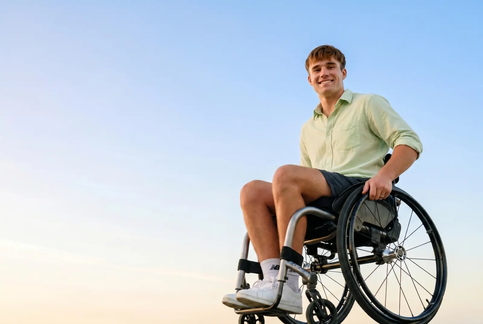 Jeune homme en fauteuil roulant souriant en extérieur
